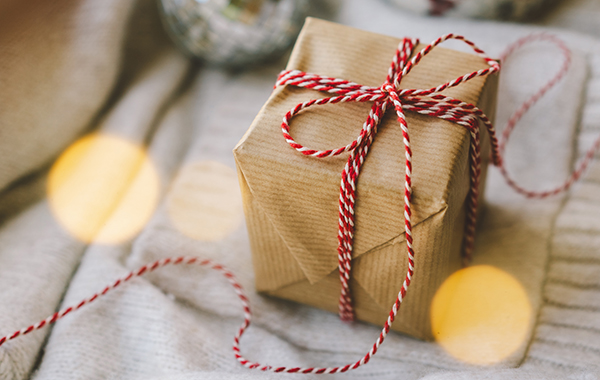 A present wrapped in a brown paper bag with a striped red and white ribbon