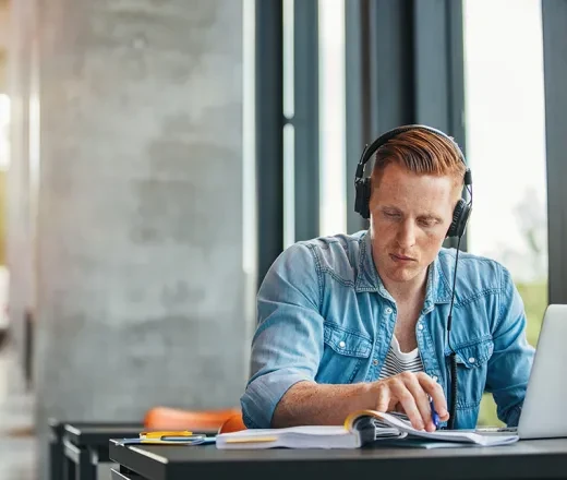 man studying on laptop wearing headphones