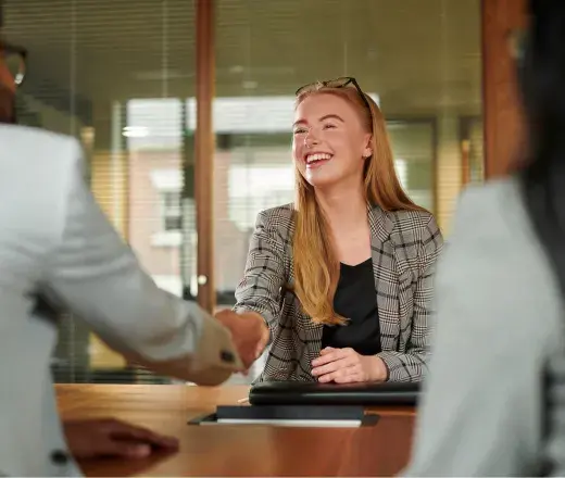 A person is shaking hands with a person in an office. Photo from Getty Images