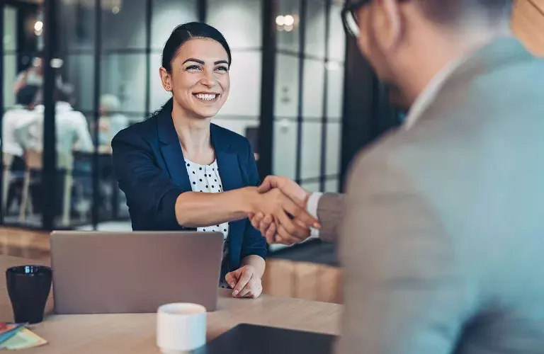 Woman on laptop shaking hands