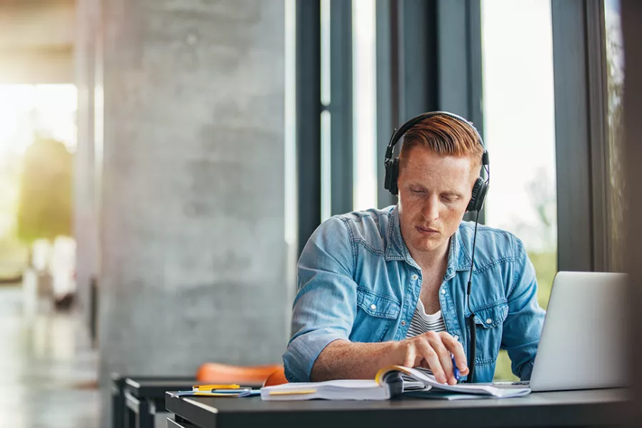 man studying on laptop wearing headphones
