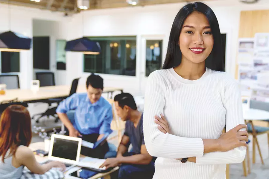 a student smiling while a group of students behind her are discussing