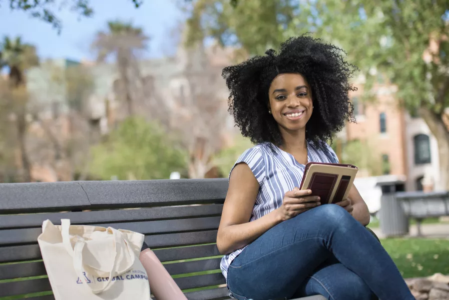 UAGC student smiling and sitting on a bench