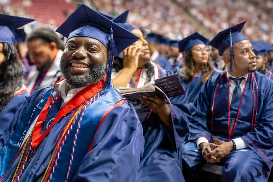 Graduates sitting and smiling in the commencement stadium