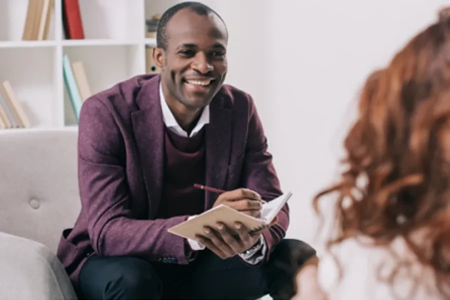 A man smiling while having a conversation and taking notes