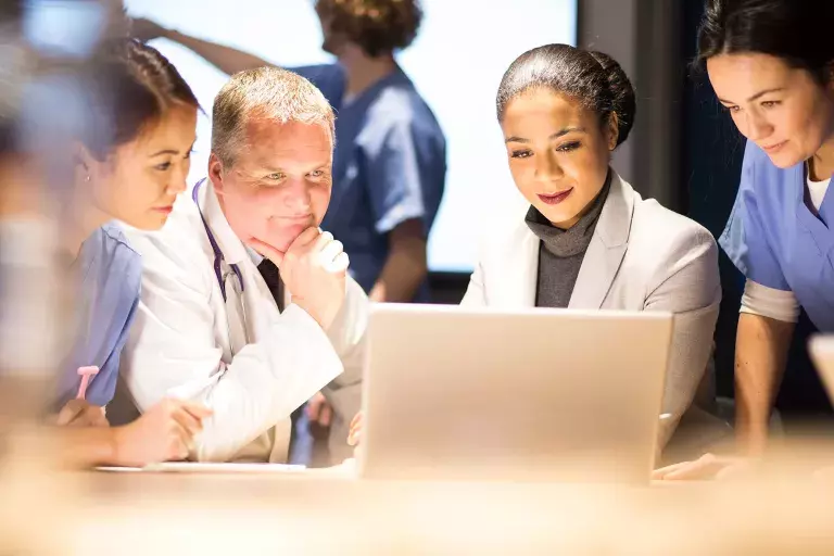 Group in a discussion in front of a laptop