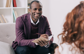 A man smiling while having a conversation and taking notes